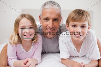 Smiling siblings and their father posing