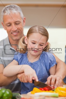 Portrait of a father showing his daughter how to cook