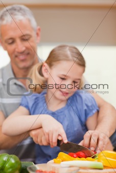 Portrait of a father slicing pepper with his daughter