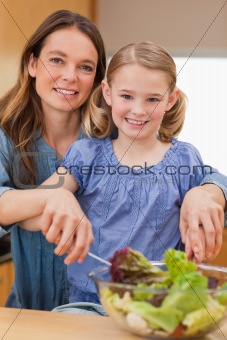 Portrait of a happy mother preparing a salad with her daughter