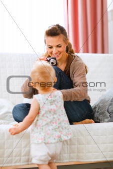 Young mother making photos of baby
