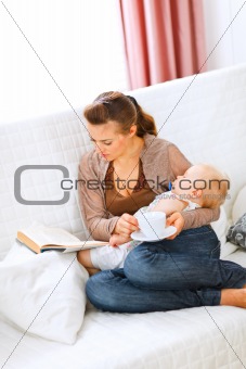 Young mom resting while baby sleep by having tea and reading book
