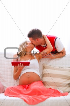 Young pregnant woman kissing her husband who present her jewelery
