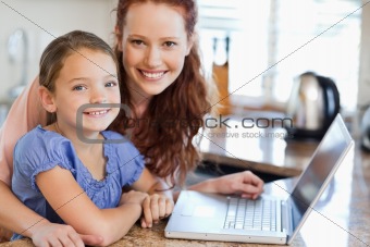 Mother and daughter with notebook in the kitchen