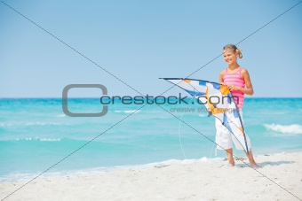 Cute girl on beach playing with a colorful kite