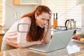 Woman annoyed by laptop in the kitchen