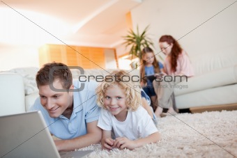 Father and son with laptop on the floor