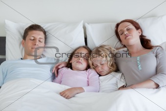 Family sleeping in the bed together