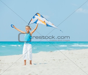 Cute girl on beach playing with a colorful kite
