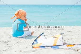 Cute boy on beach playing with a colorful kite