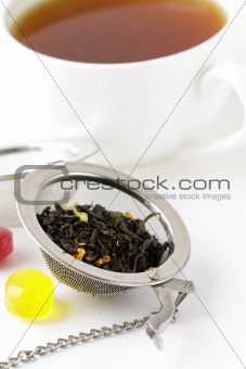 tea strainer with a fragrant black tea and cup in the background