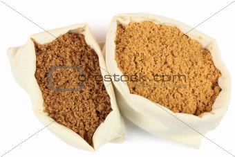 Two types brown sugar in white fabric bags. 