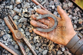 Detail of dirty hand holding horseshoe - blacksmith