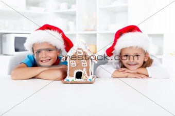 Happy kids with gingerbread house at christmas