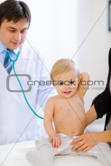 Portrait of happy baby being checked by pediatric doctor using a stethoscope 
