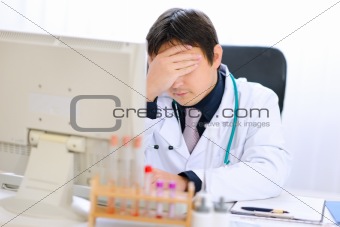 Tired medical doctor working on computer at office
