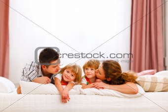 Family portrait of mom dad and twins daughters on bed
