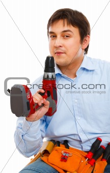Construction worker blowing smoke off electric screwdriver 
