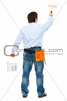 Construction worker with bucket and brush painting. Back view
