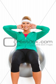 Fitness girl making abdominal crunch on fitness ball isolated on white
