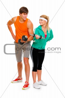 Young man and fitness girl lifting a dumbbell isolated on white
