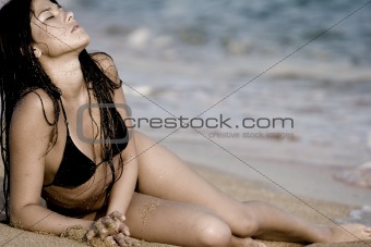 The girl lying on the sand at the beach with your eyes closed