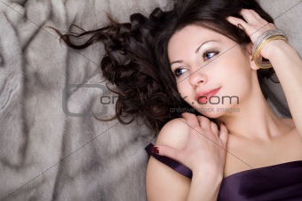 Sexy girl lying on grey fur coat
