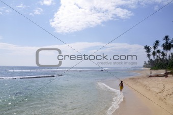A man walking down the beach on a bright sunny day