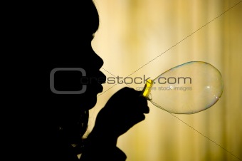 Little girl making bubble silhuette closeup