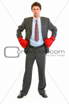 Full length portrait of serious modern businessman in boxing gloves
