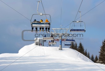 Skiers in chairlift arriving to top of mountain