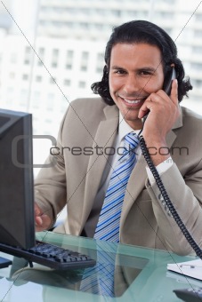 Portrait of a businessman working with a monitor while being on the telephone