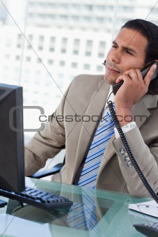 Portrait of a handsome businessman working with a monitor while being on the phone
