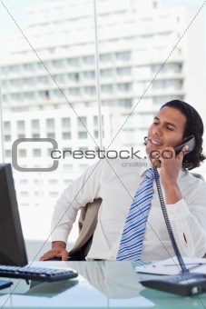 Portrait of a businessman on the phone while looking at his computer