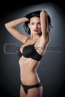 beautiful woman with dark hair in sexy black underwear over gray