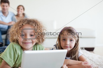 Smiling children using a tablet computer while their happy parents are watching