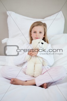 Girl hugging her teddy on the bed