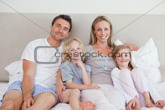 Smiling family sitting on the bed