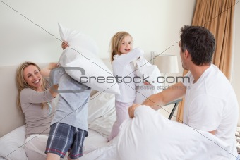 Playful family having a pillow fight in the bedroom