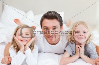 Father lying on the bed with his children