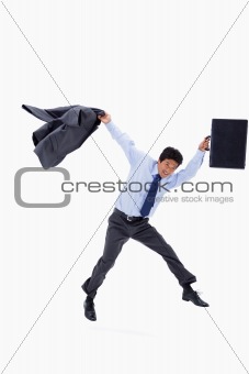 Businessman jumping while holding his jacket and a briefcase