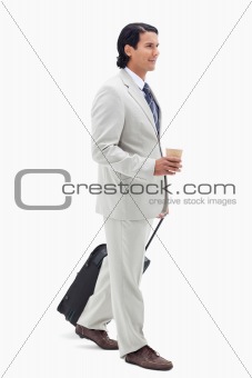 Portrait of a businessman with a takeaway coffee and a suitcase