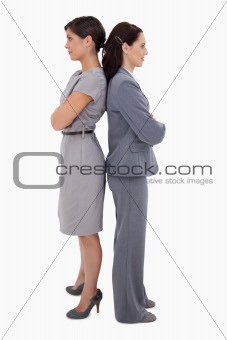 Businesswomen with arms folded standing back on back