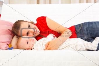 Smiling mother with baby laying on couch