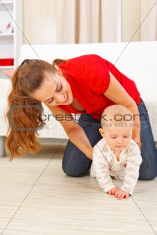 Mother helping cheerful baby learn to creep