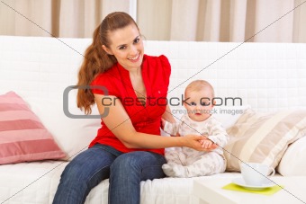 Baby sitting with mother on sofa