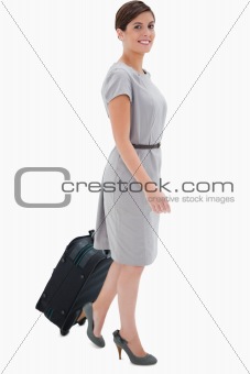 Side view of smiling woman with wheely bag
