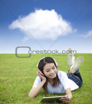 happy girl using touch pad computer with headphone on  the meadow