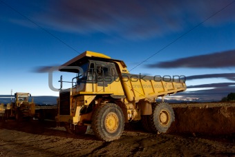 Huge auto-dump yellow mining truck night shot and excavator