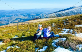 Children rest on autumn  mountain plateau with first winter snow